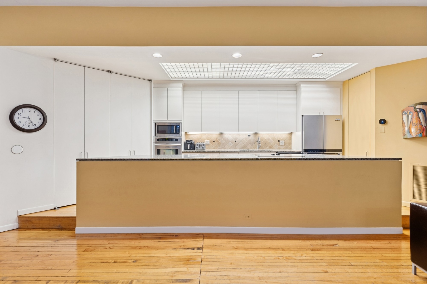 957 West Huron Street, Unit 2 Chicago, IL 60642 - Photo 5 of 26 a view of room with kitchen island stainless steel appliances wooden floor and window