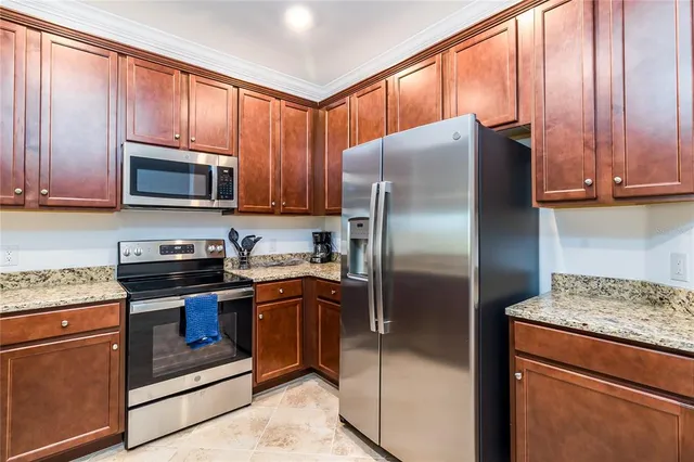 a kitchen with granite countertop a refrigerator stove and microwave