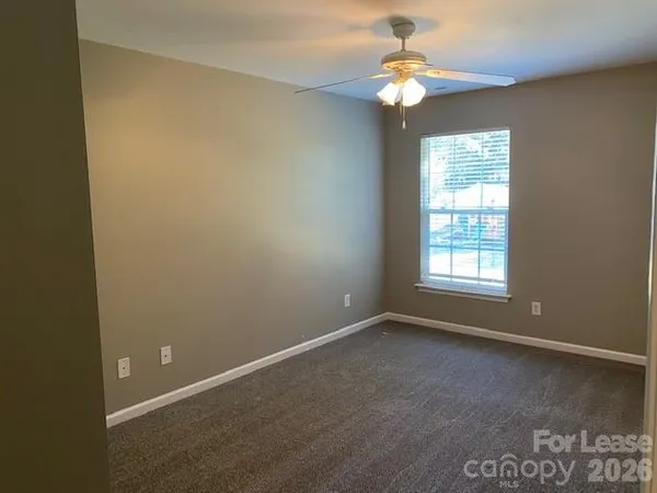 an empty room with a window and a fan