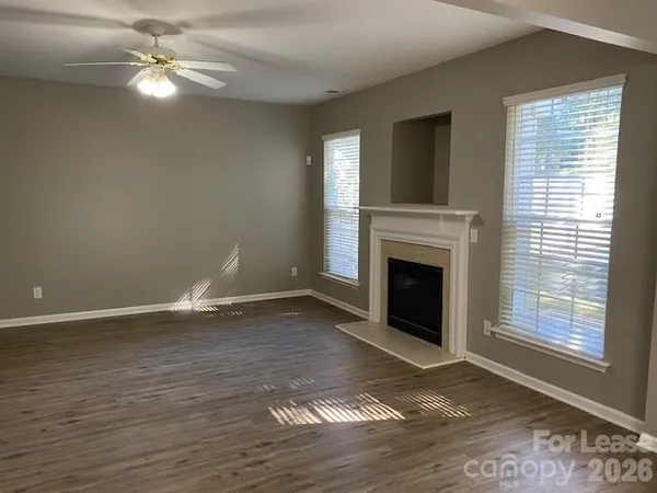 a view of a livingroom with a fireplace a ceiling fan and wooden floor