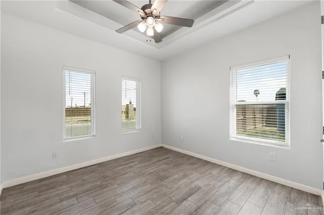 a view of an empty room with a window and wooden floor