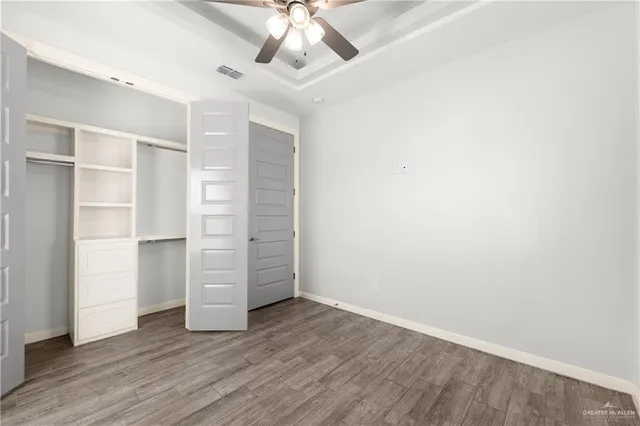 an empty room with wooden floor closet and windows