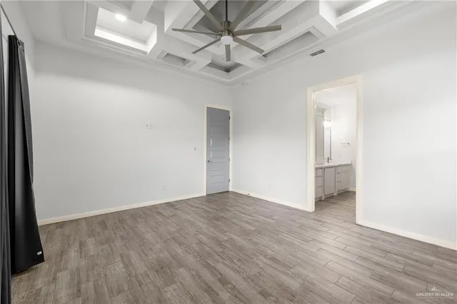 an empty room with wooden floor and a ceiling fan