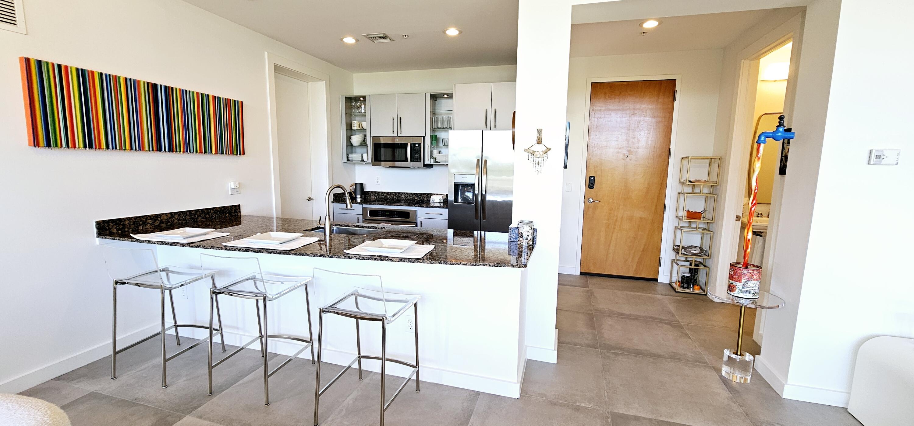 365 Southeast 6th Avenue, Unit 305 Delray Beach, FL 33483 - Photo 12 of 49 a kitchen with stainless steel appliances kitchen island granite countertop a table and chairs