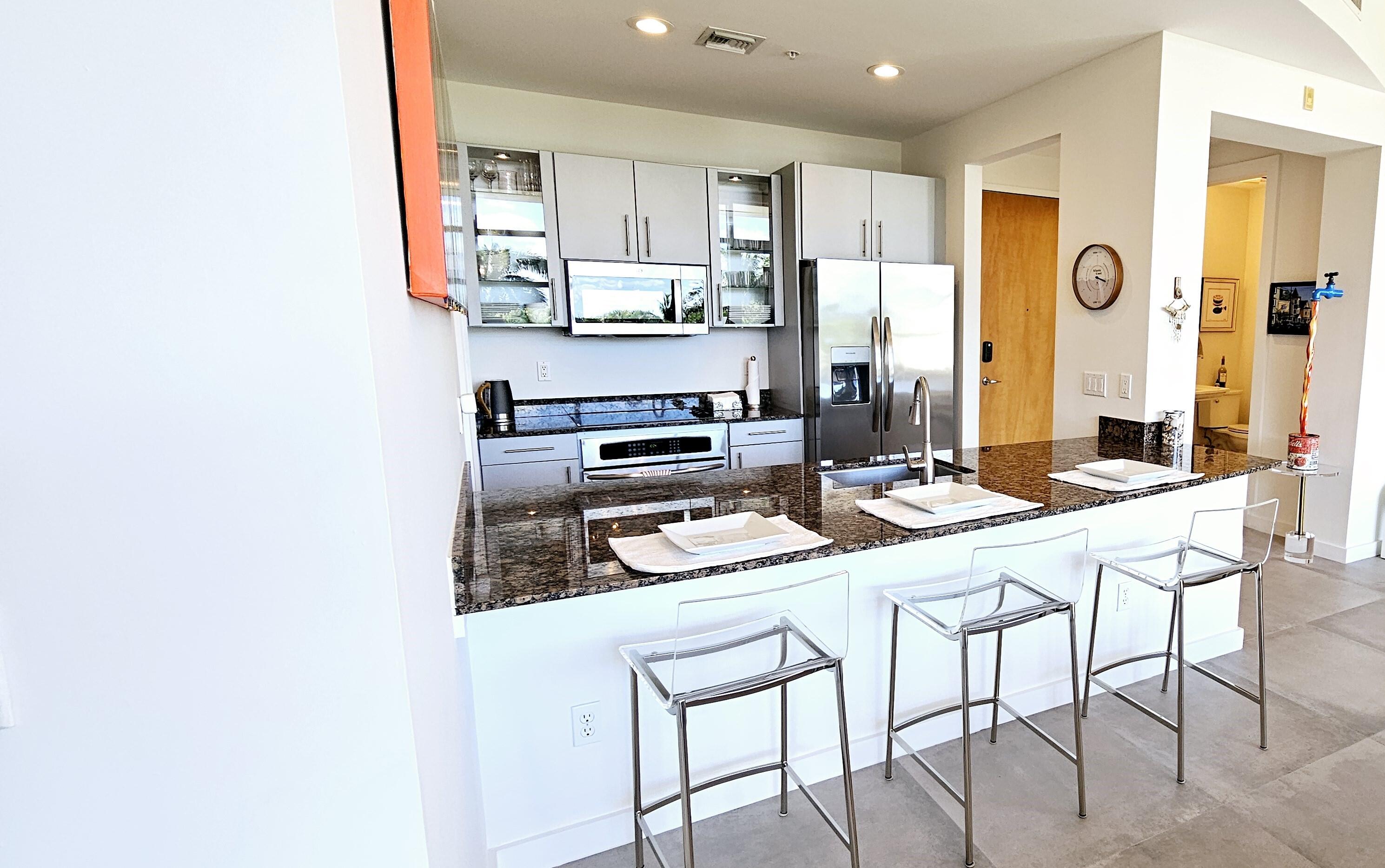 365 Southeast 6th Avenue, Unit 305 Delray Beach, FL 33483 - Photo 13 of 49 a kitchen with stainless steel appliances kitchen island granite countertop a refrigerator and a stove top oven