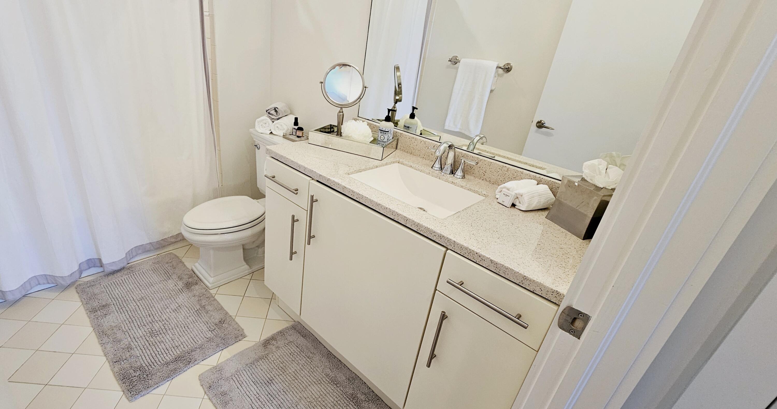 365 Southeast 6th Avenue, Unit 305 Delray Beach, FL 33483 - Photo 27 of 49 a bathroom with a sink and mirror with toilet