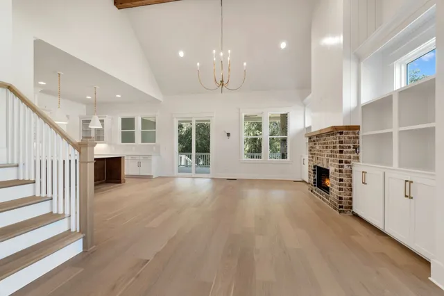 a view of a livingroom with a fireplace a chandelier and windows