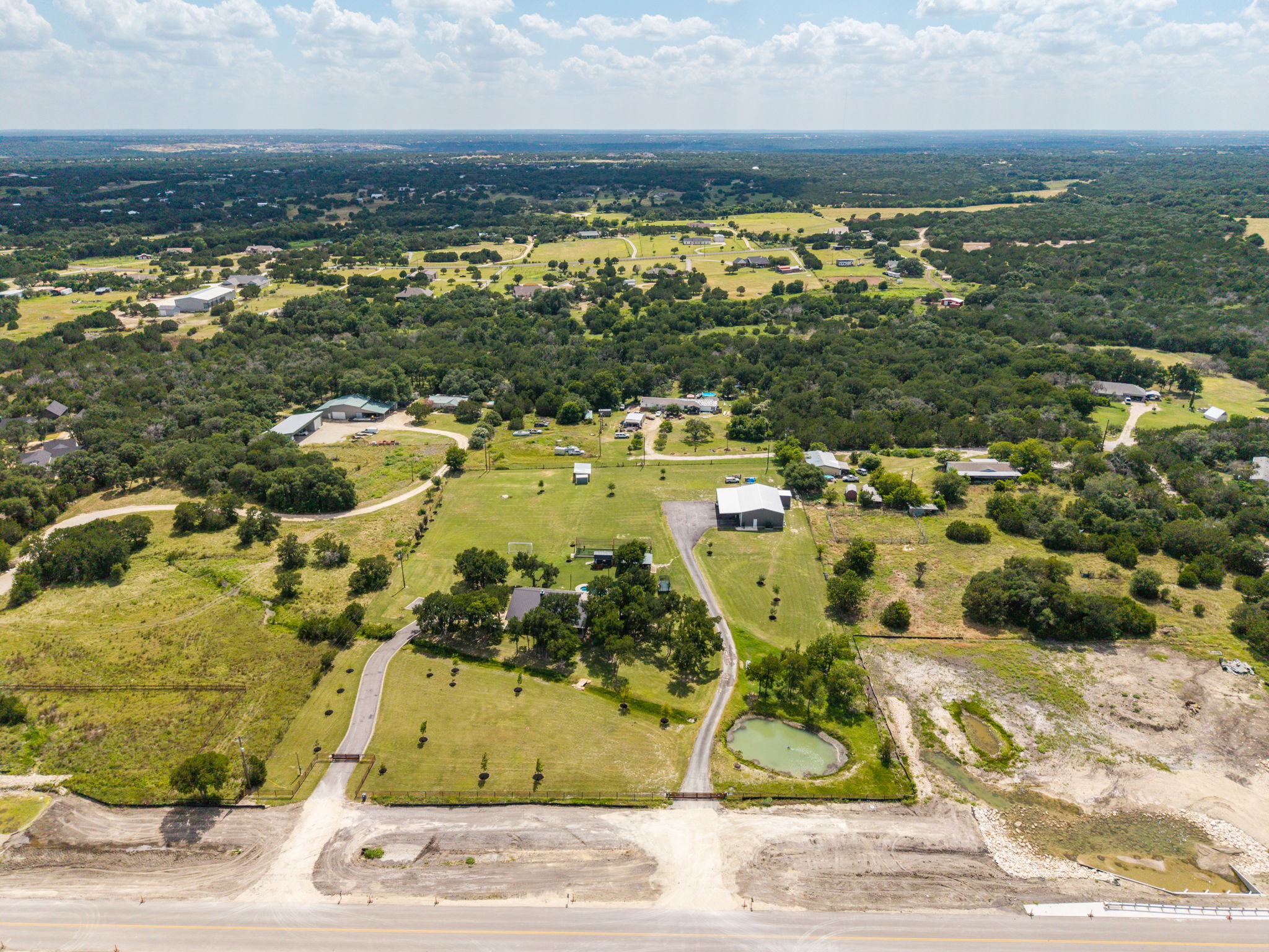 3001 County Road 255 Georgetown, TX 78633 - Photo 33 of 35 An aerial perspective reveals a sprawling rural landscape with abundant trees and a tranquil pond.