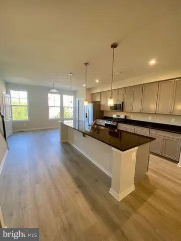 a view of kitchen and empty room with wooden floor
