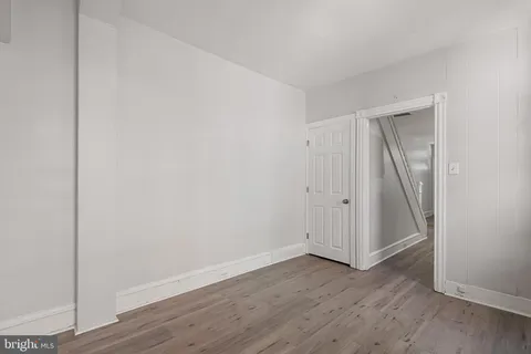 a view of an empty room with wooden floor and closet