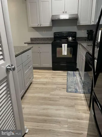 a kitchen with granite countertop a stove a sink and a microwave