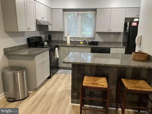 a kitchen with granite countertop a stove a sink and a refrigerator