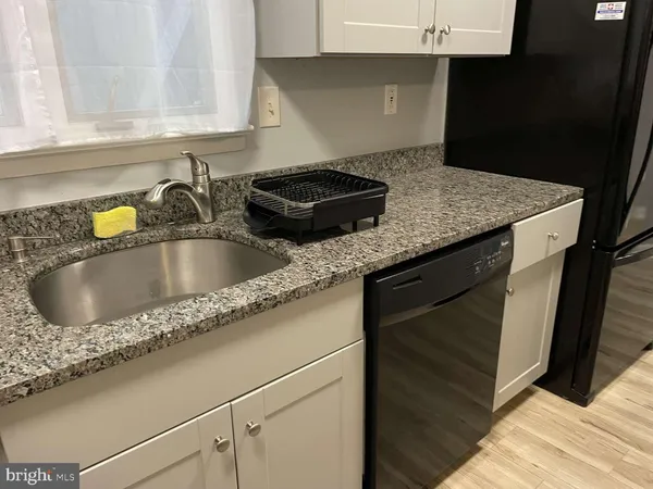 a kitchen with granite countertop a sink dishwasher and cabinets with wooden floor