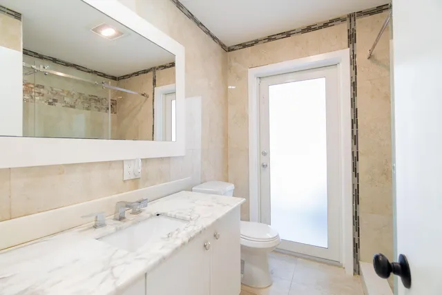 a bathroom with a granite countertop toilet a sink and shower