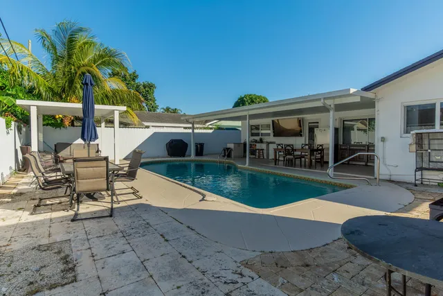 an aerial view of a house with swimming pool and large trees