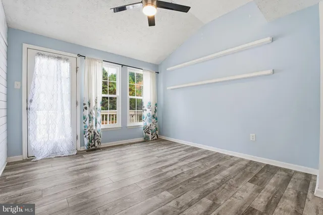 an empty room with wooden floor fan and windows