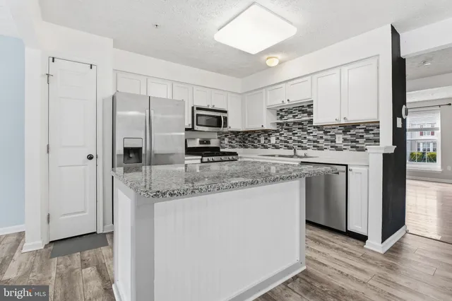 a kitchen with stainless steel appliances granite countertop a refrigerator a stove and a sink