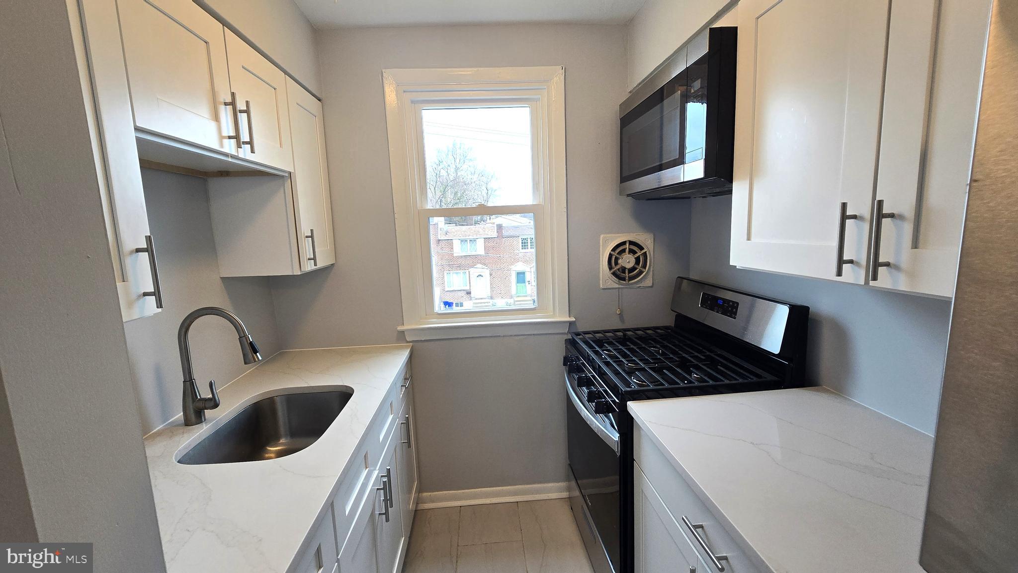 5099 Palmers Mill Road, Unit 2 Clifton Heights, PA 19018 - Photo 5 of 11 a kitchen with granite countertop a sink a stove and cabinets