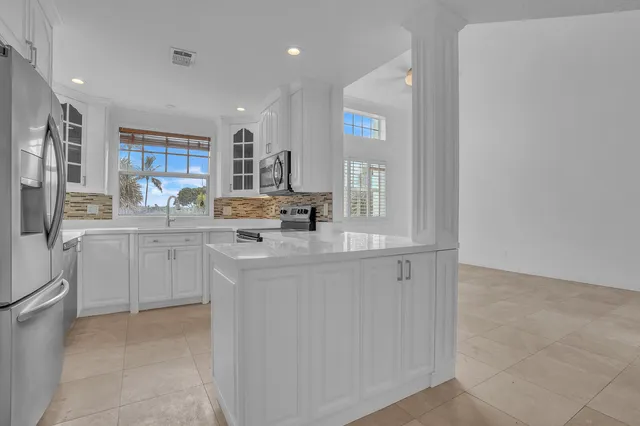 a kitchen with white cabinets and sink