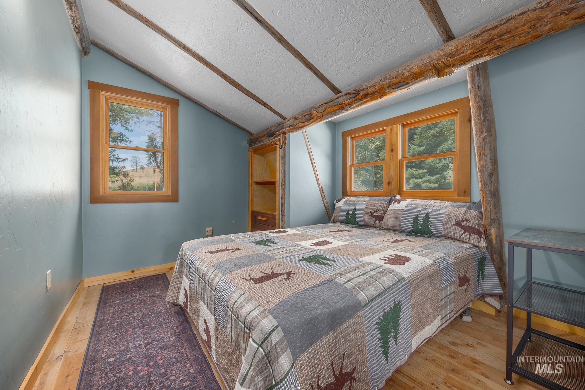 2150 Seid Creek Road Cambridge, ID 83610 - Photo 25 of 50 Slanted ceiling room featuring exposed wood beams, natural wood-frame windows, and light wood-finish flooring