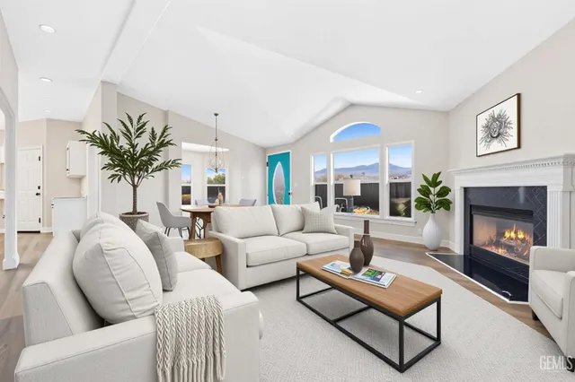 a living room with furniture a fireplace a large window and a potted plant