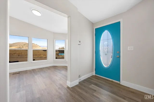 an empty room with wooden floor mirror and windows