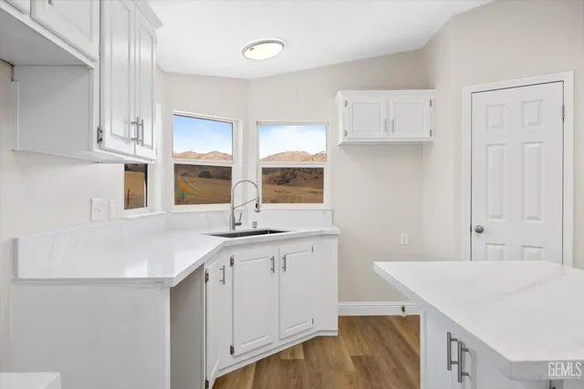 a kitchen with stainless steel appliances granite countertop a sink and white cabinets with wooden floor