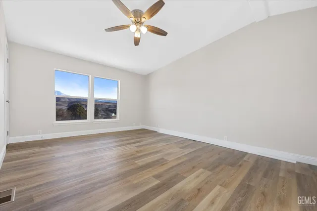 an empty room with wooden floor and a ceiling fan