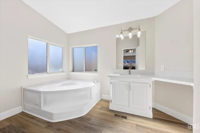 a spacious bathroom with a double vanity sink mirror and bathtub