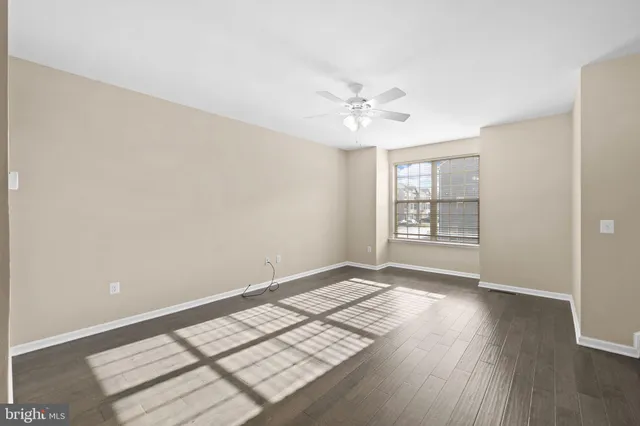 an empty room with wooden floor fan and windows