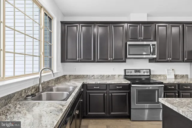 a kitchen with granite countertop a stove sink and microwave