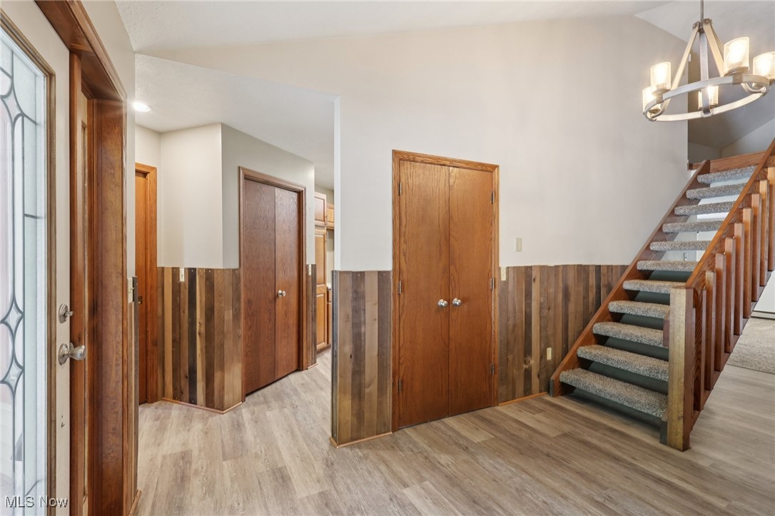 5643 Chapin Road Madison, OH 44057 - Photo 7 of 50 Foyer featuring wainscoting, lofted ceiling, light wood-style flooring, stairway, and a chandelier