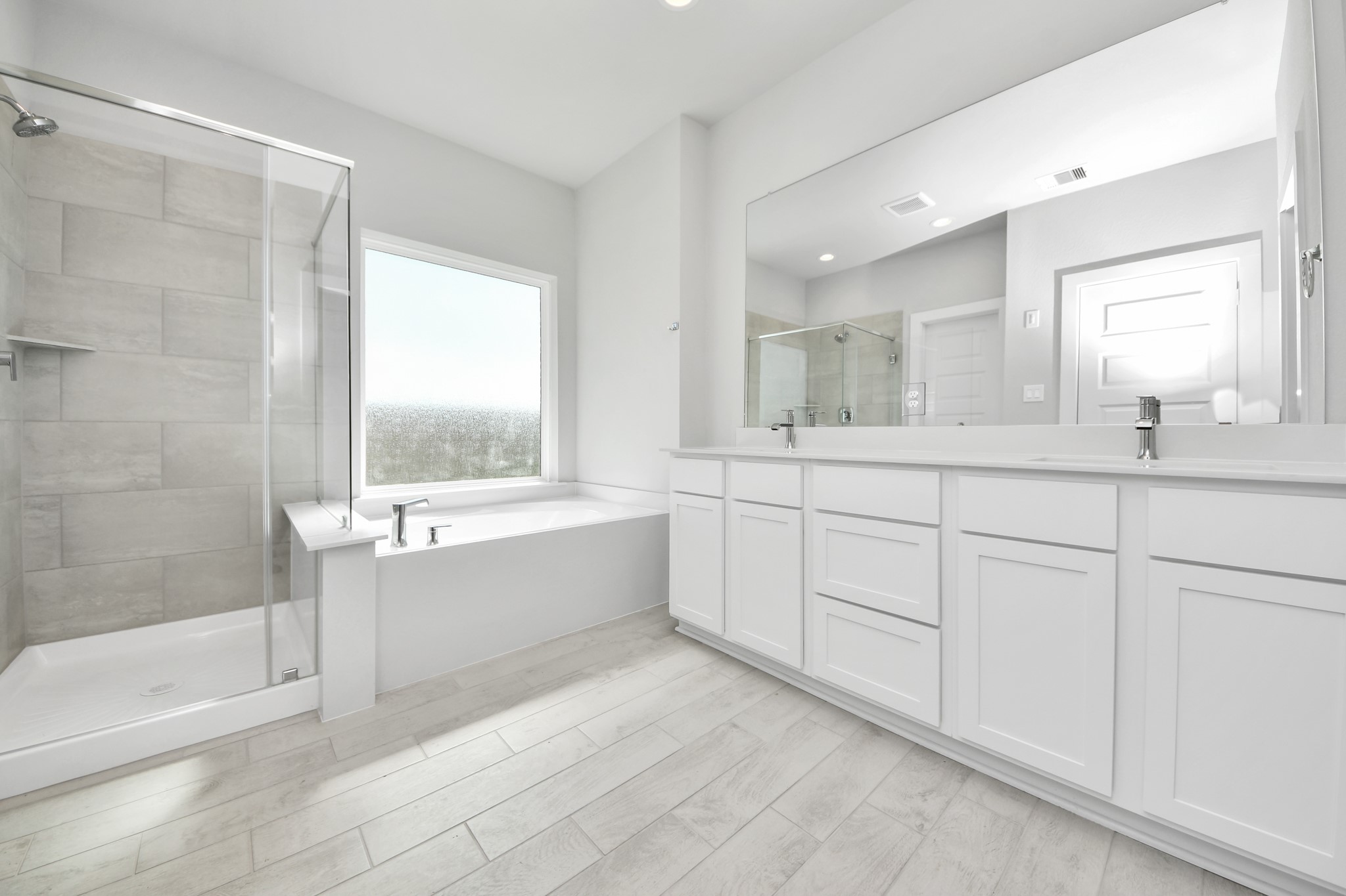 2910 Burris Park Drive Spring, TX 77373 - Photo 21 of 34 Escape to a spa-like oasis in this primary bathroom. Enjoy a walk-in shower with tile surround, a separate garden tub with custom detailing, and an elegant vanity featuring light countertops, modern hardware, and beautiful vanity lights. Experience luxury and relaxation in every detail. Sample photo of completed home with similar floor plan. Actual colors and selections may vary.
