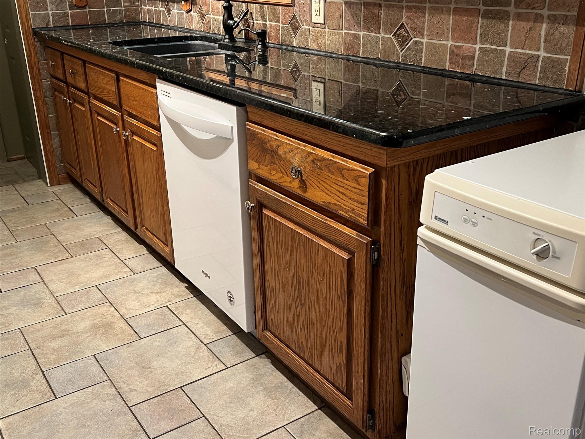 36795 Greenbush Road Wayne, MI 48184 - Photo 3 of 61 Kitchen featuring tasteful backsplash, light tile patterned floors, white dishwasher, brown cabinets, and dark stone counters