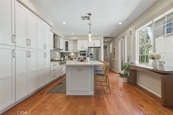 a kitchen with stainless steel appliances granite countertop a refrigerator a sink dishwasher a stove with white cabinets and wooden floor