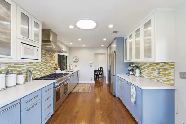 a large kitchen with stainless steel appliances a sink and cabinets