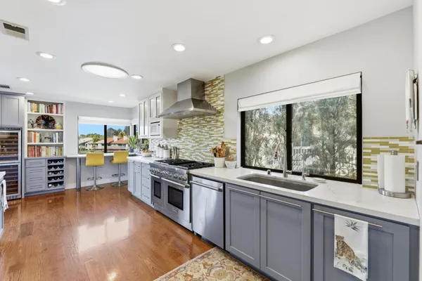a large kitchen with stainless steel appliances granite countertop a large window and a counter space