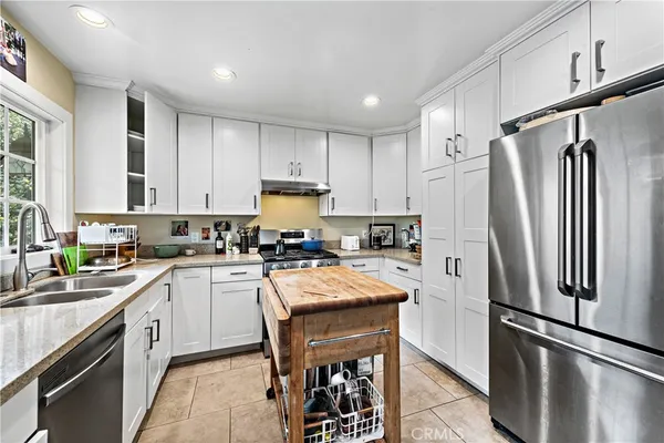 a kitchen with a refrigerator a sink and white cabinets