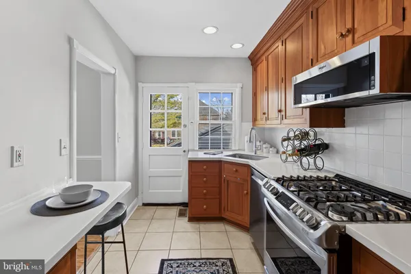 a kitchen with stainless steel appliances granite countertop a refrigerator a stove a sink and a window