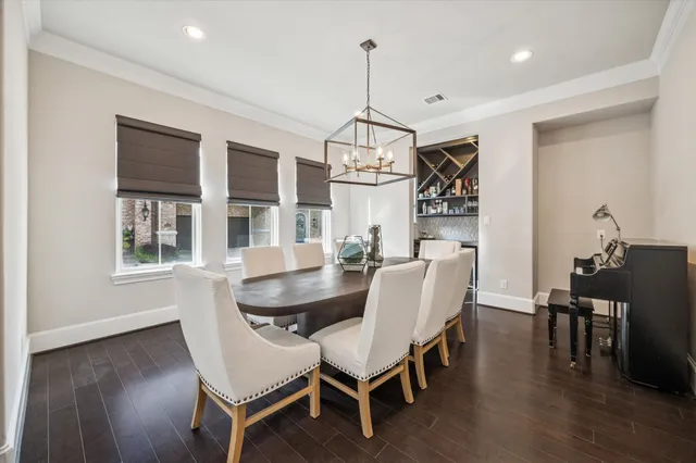a dining room with wooden floor a chandelier a glass table and chairs