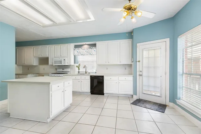 a kitchen with a stove a sink and dishwasher with white cabinets