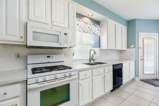 a kitchen with white cabinets appliances and a sink