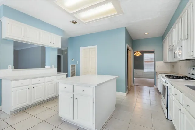 a view of an empty room with window and cabinet area