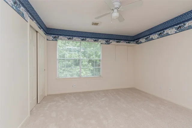 an empty room with windows and fan