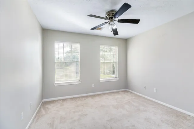 an empty room with ceiling fan and window