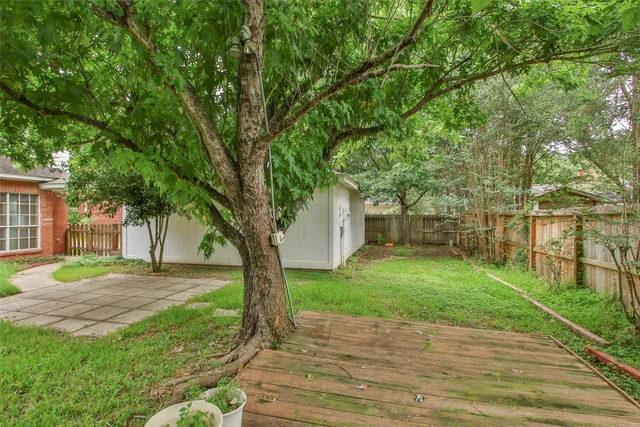 a backyard of a house with potted plants and large trees