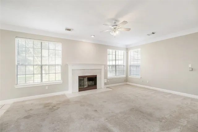 a view of an empty room with chandelier fan and fire place