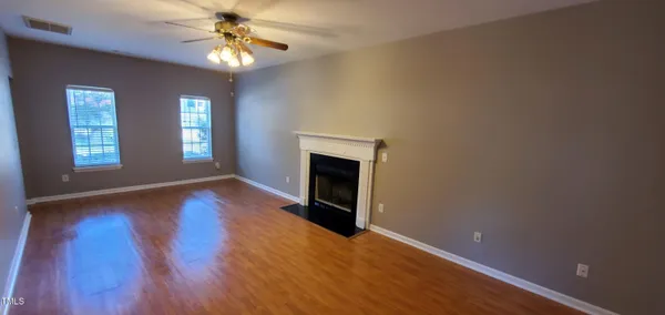 a view of an empty room with window and wooden floor
