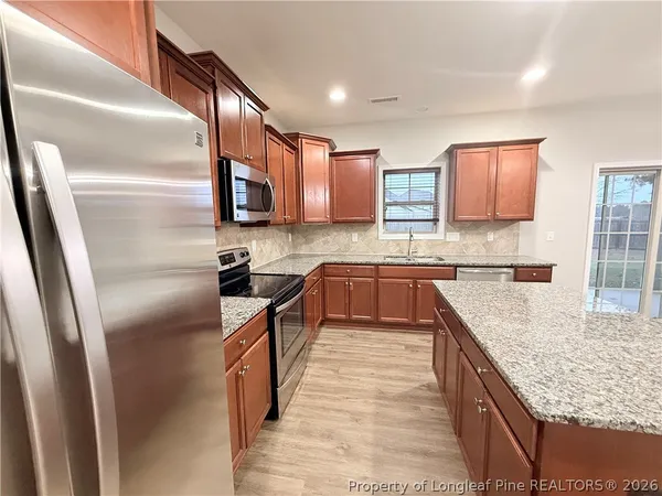 a kitchen with stainless steel appliances granite countertop a refrigerator a stove and a sink