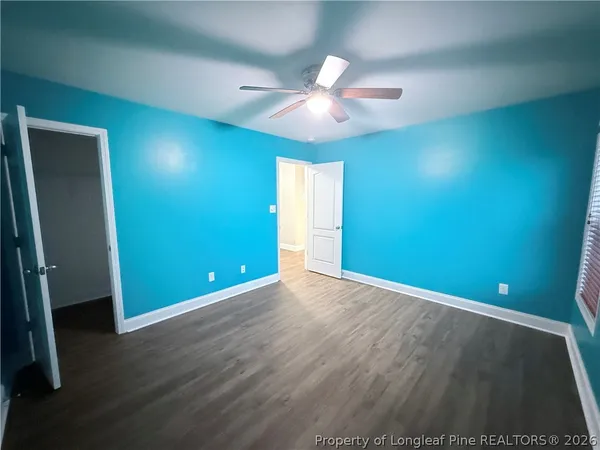 an empty room with wooden floor and fan